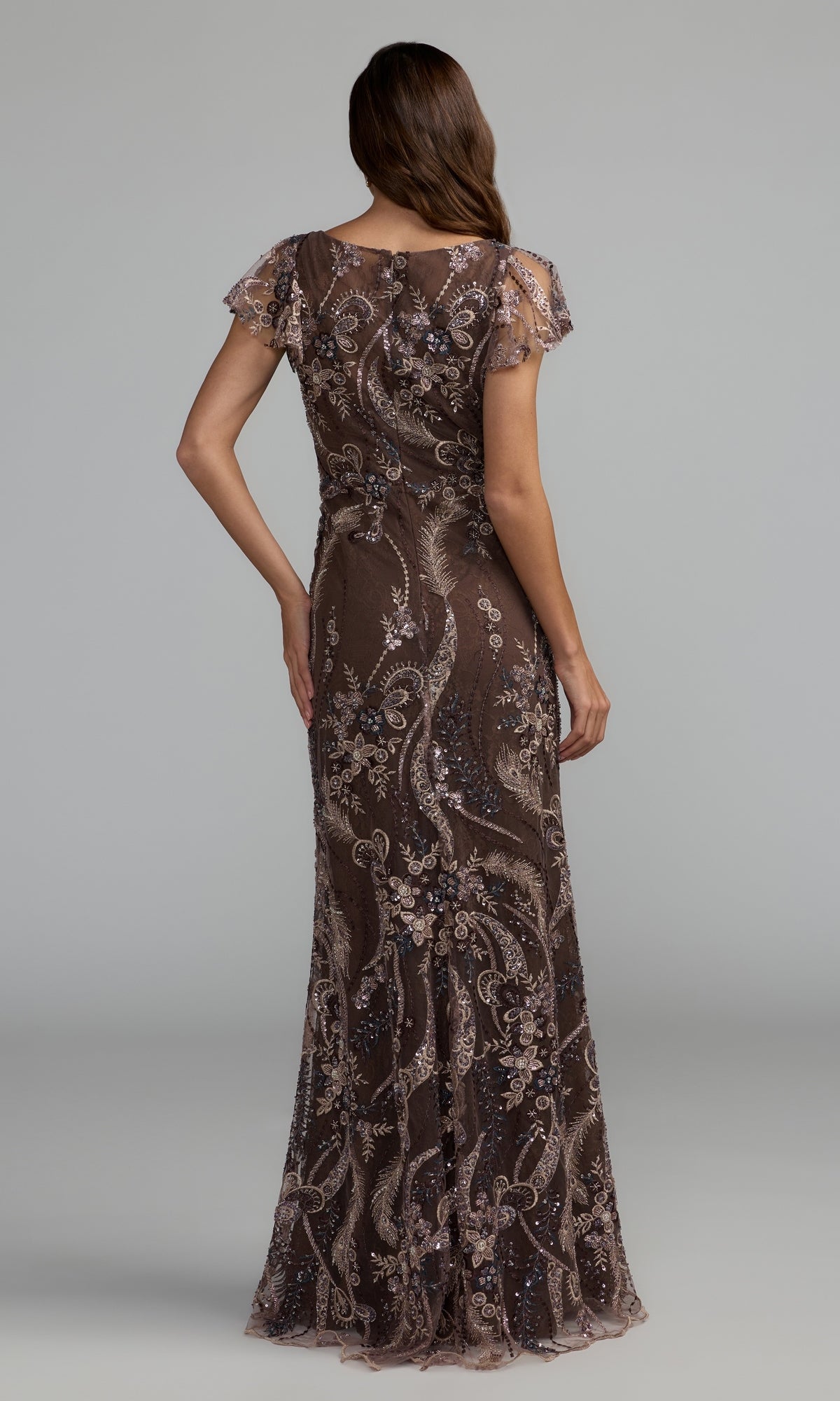 A woman is shown from the back wearing the Mac Duggal 68914 long formal dress—a floor-length, short-sleeve brown gown adorned with intricate sequin and bead embellishments—set against a plain gray background.